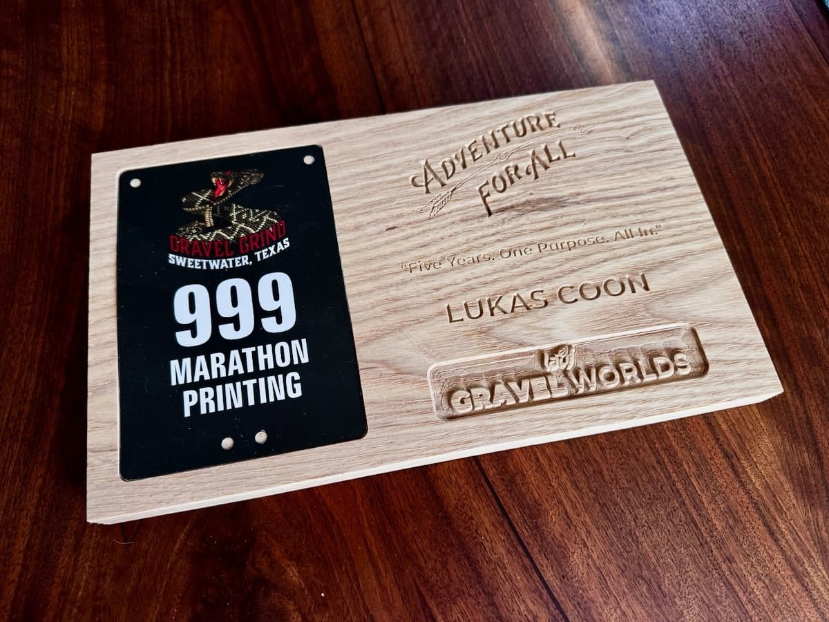 CNC-engraved ash wood trophy plaque with Adventure for All branding, personalized for Lukas Coon, featuring a number plate holder slot on the left and Gravel Worlds logo.