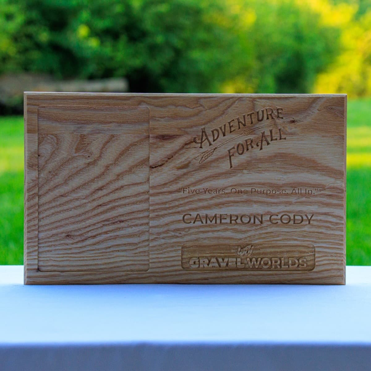 Close-up of ash wood trophy plaque for Cameron Cody, showing detailed CNC engraving of Adventure for All logo and tagline "Five Years. One Purpose. All In."