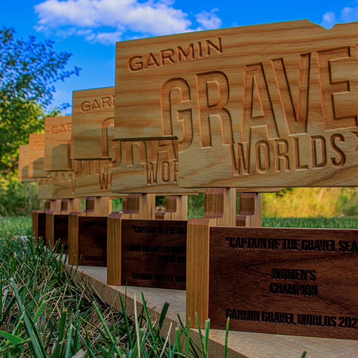 Close-up detail view of three trophies with engraved "GARMIN GRAVEL WORLDS" text and darker base plaques