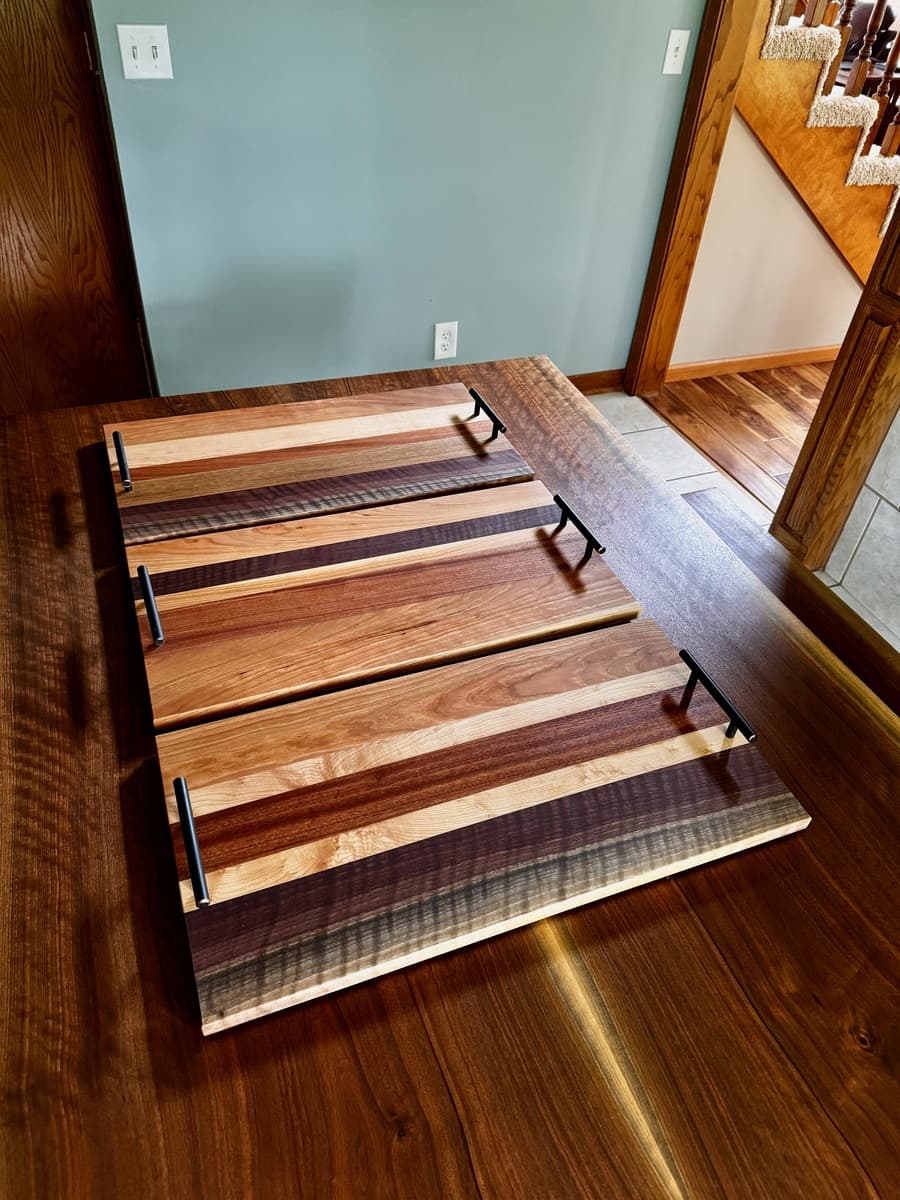 Collection of striped wooden number plate holders displaying contrasting wood colors from light ash to dark walnut with black metal handles