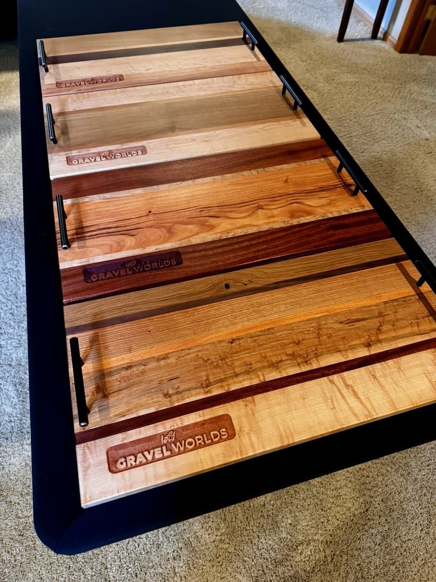 Overhead view of eight wooden trophy plaques arranged in a grid, displaying different wood grains and stain colors ranging from light ash to dark walnut with engraved text