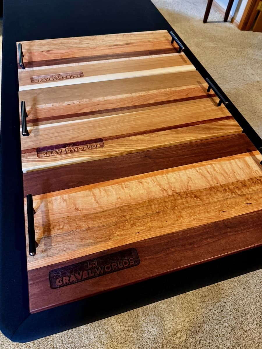 Three wooden trophy plaques displayed at angles showing varied wood species and engraved Gravel Worlds branding on each plaque