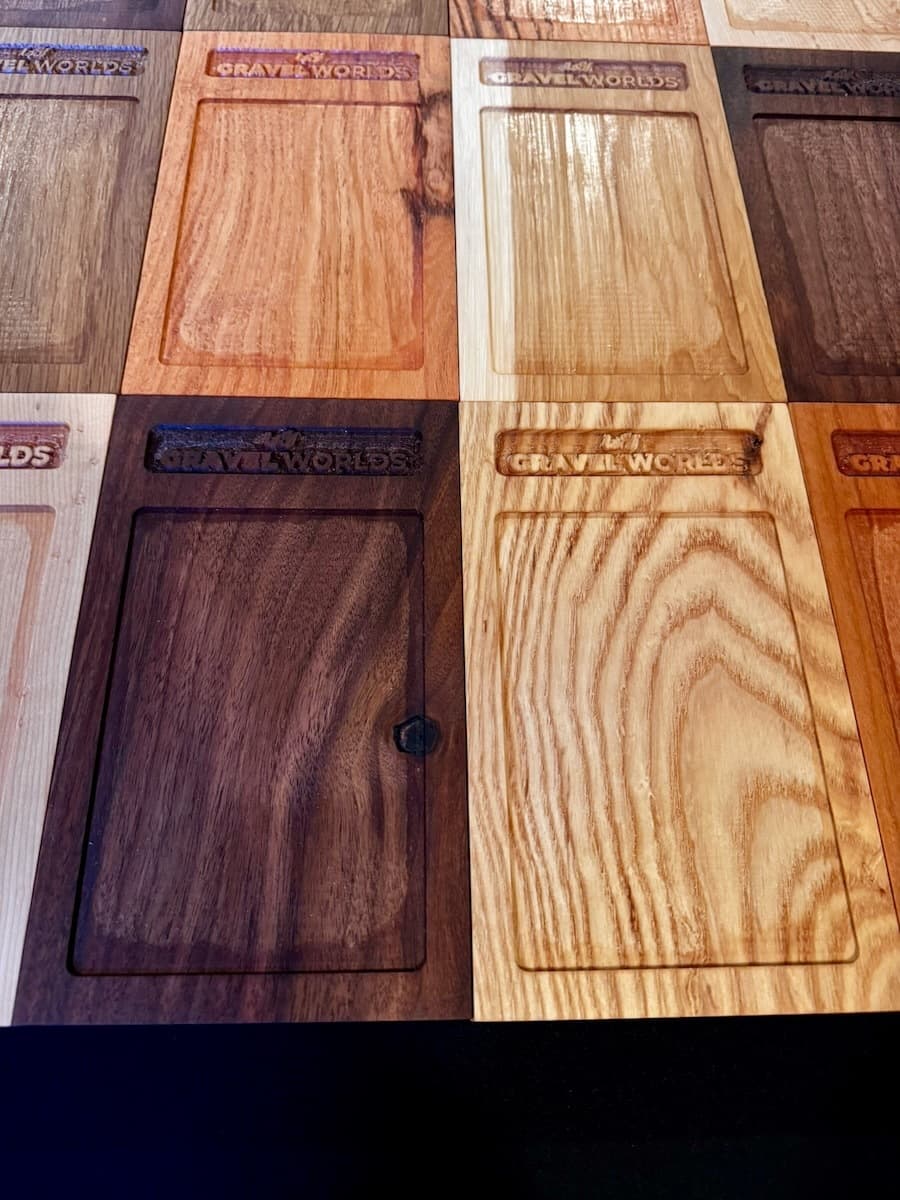Close-up detail of three wooden trophy plaques showing engraved Gravel Worlds text and wood grain variations