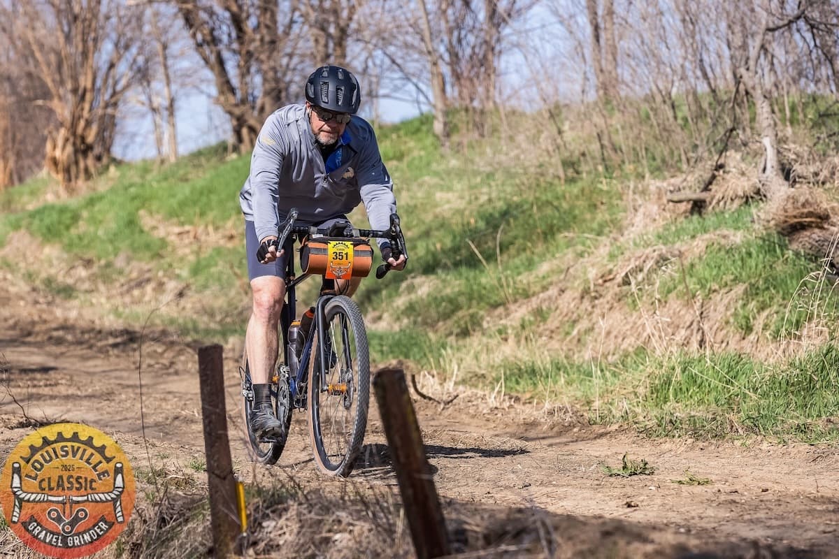 Cyclist riding gravel bike on dirt trail during Louisville Classic Gravel Grinder race event with number 351 bib displayed
