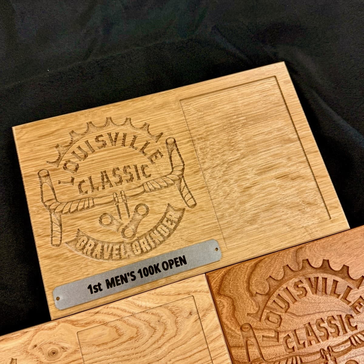White oak trophy plaque with engraved Louisville Classic Gravel Grinder logo and sword design featuring 1st Men's 100K Open race category with blue label