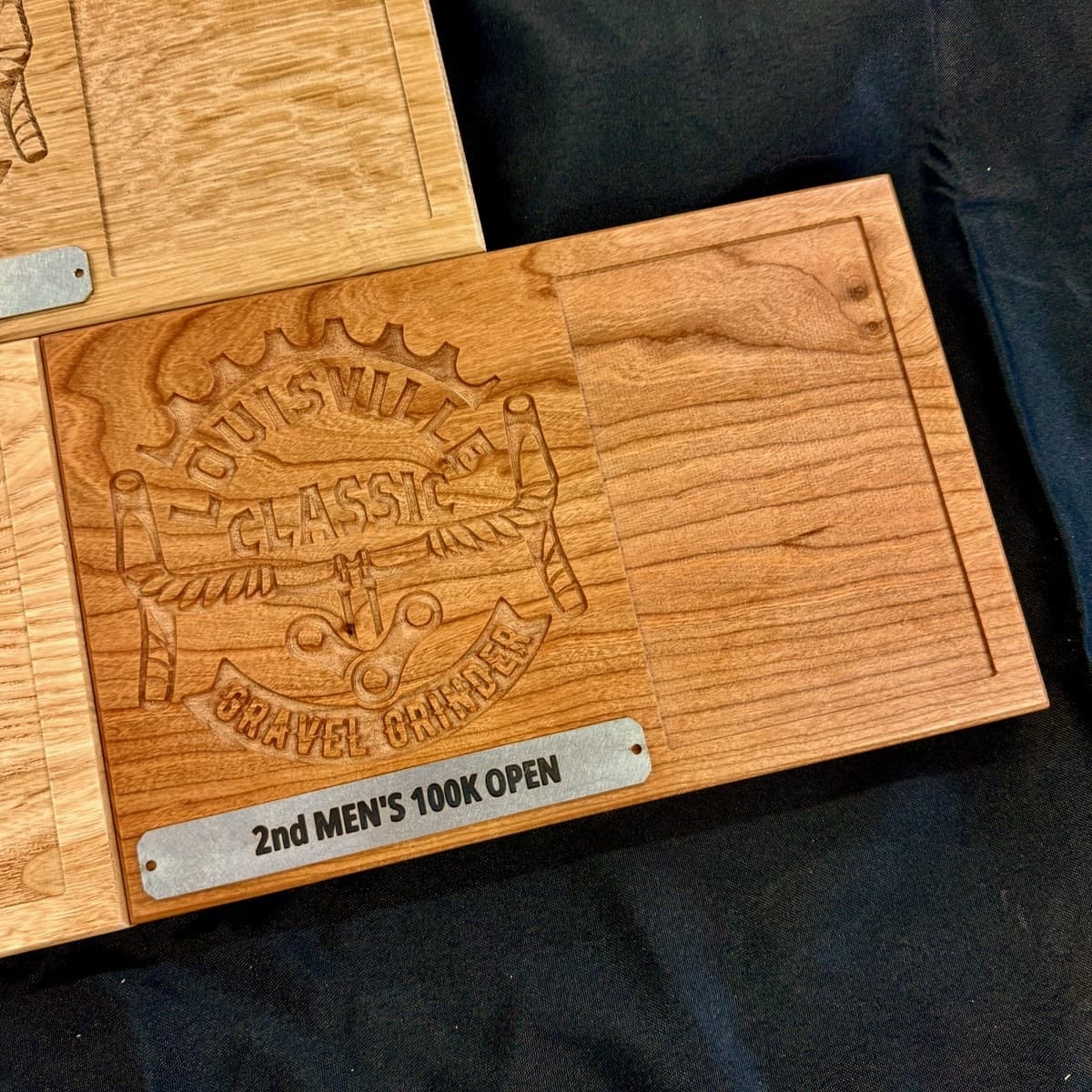Cherry wood trophy plaque with engraved Louisville Classic branding and sword graphic showing 2nd Men's 100K Open category with blue label