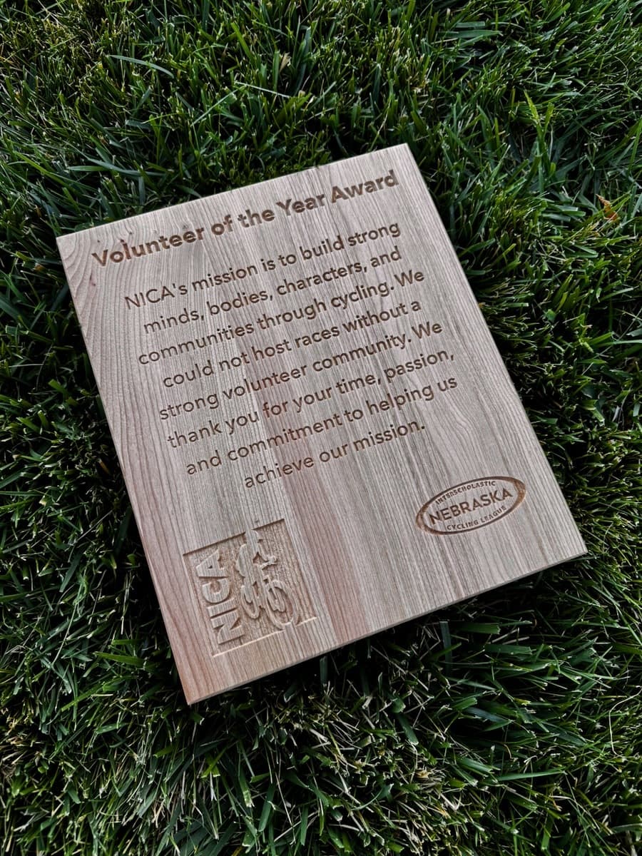 Cherry wood Volunteer of the Year NICA award with engraved text describing NICA's mission to build strong minds, bodies, and characters through cycling