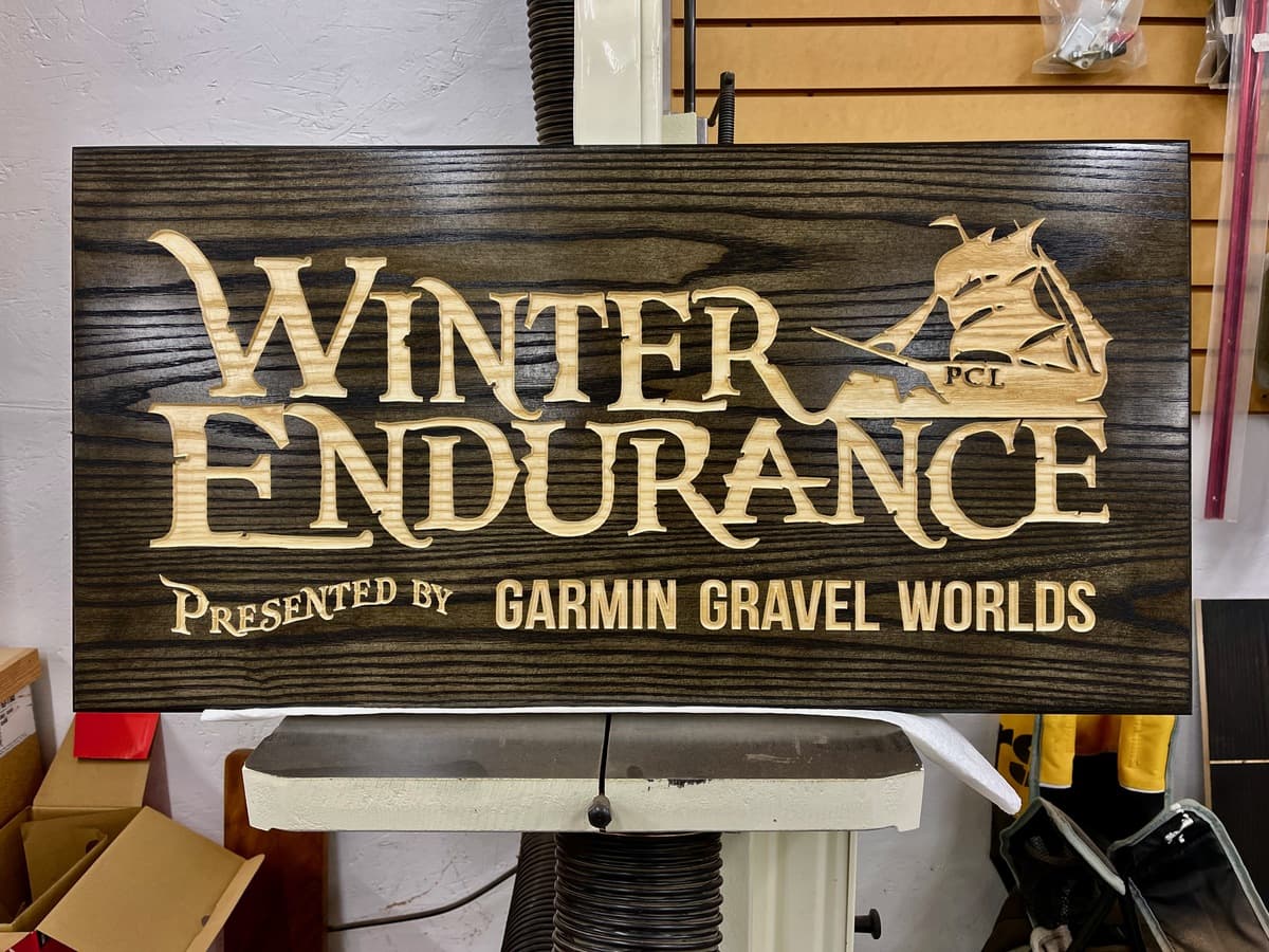 Collection of Winter Endurance 2023 trophy plaques showing varied wood species and finishes with detailed engraving work for race categories
