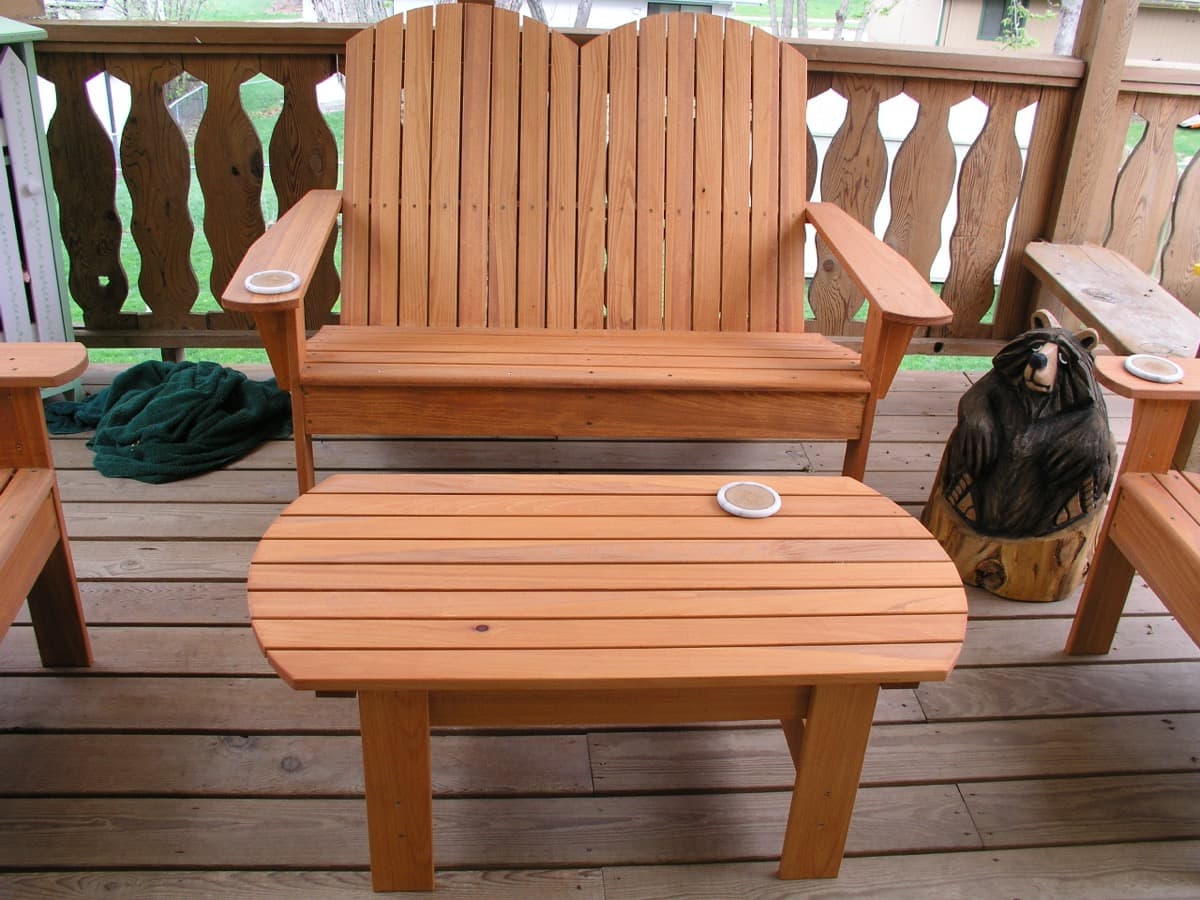 Cypress adirondack bench with side table and matching footstools arranged on deck, featuring dark stain finish with natural wood grain visible
