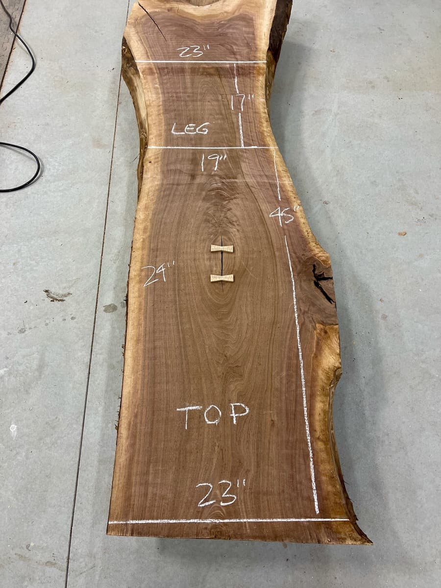 Waterfall table - live edge walnut slab marked with dimensions and layout lines during planning phase, showing measurements for top, legs, and width