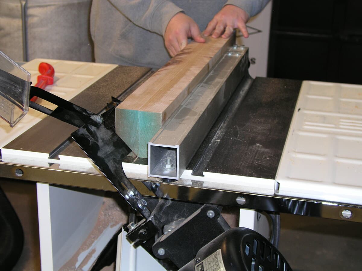 Craftsperson's hands sanding curly maple apron with hand plane on workbench, showing wood grain detail and craftsmanship