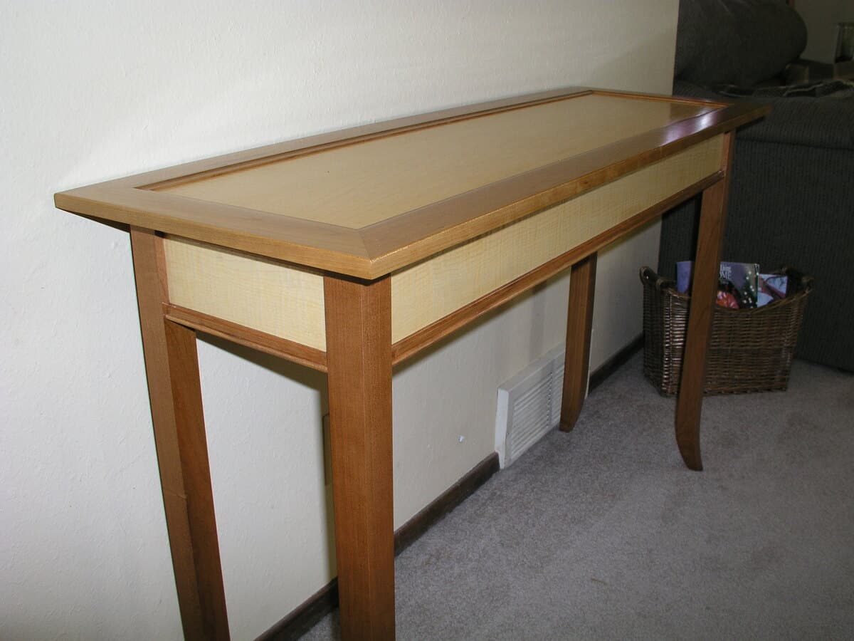 Finished cherry and curly maple console table in residential interior setting, showing curved legs and mortise and tenon joinery with natural wood finish