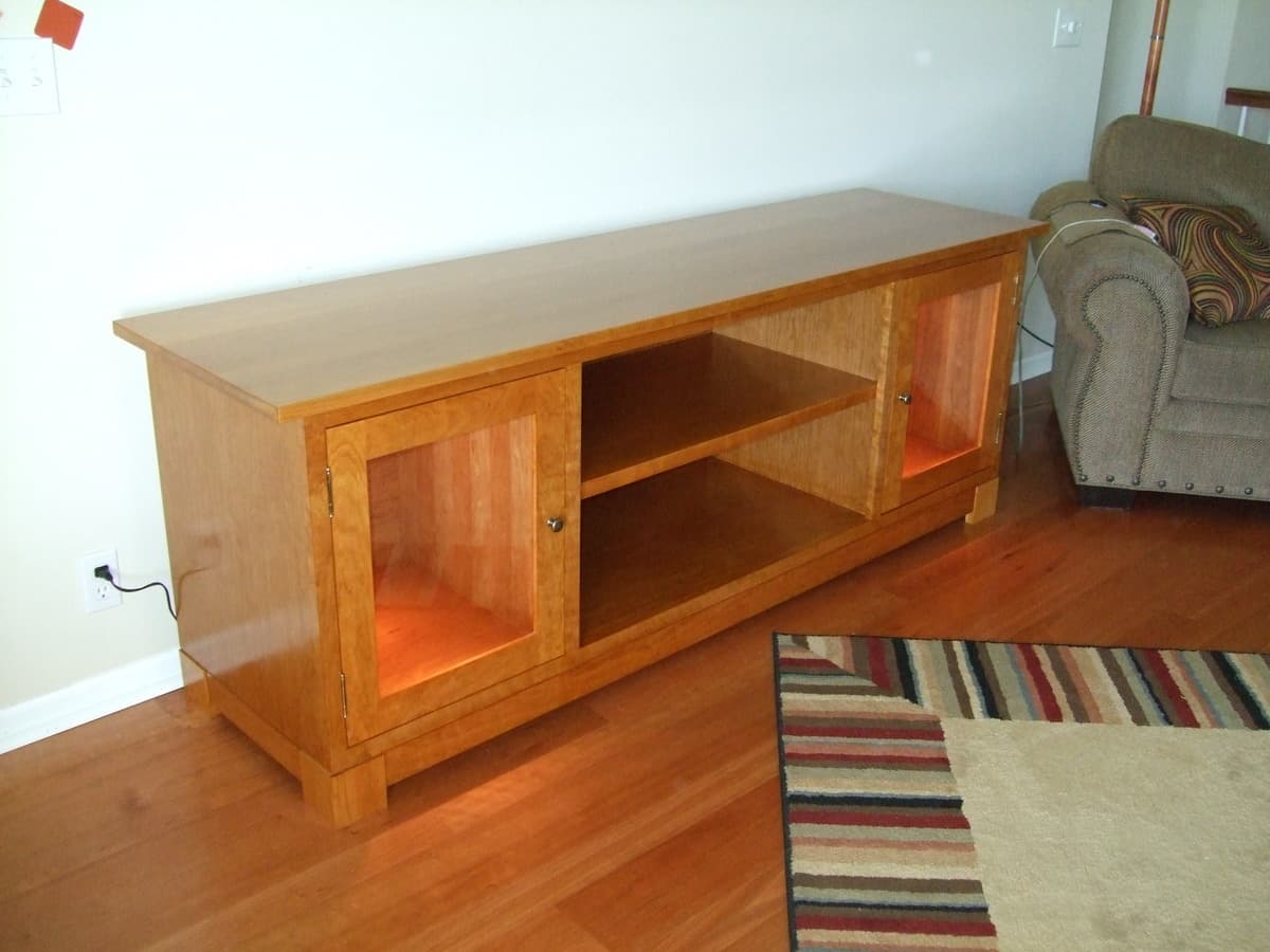 Cherry TV stand front view showing finished piece with door panels and open shelving, displaying warm wood grain with Waterlox Original finish