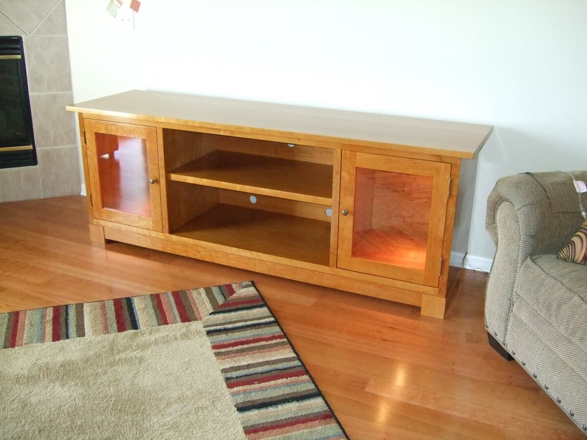 Cherry TV stand side angle view showing full cabinet design with left door panel, center open shelf, and right door panel construction