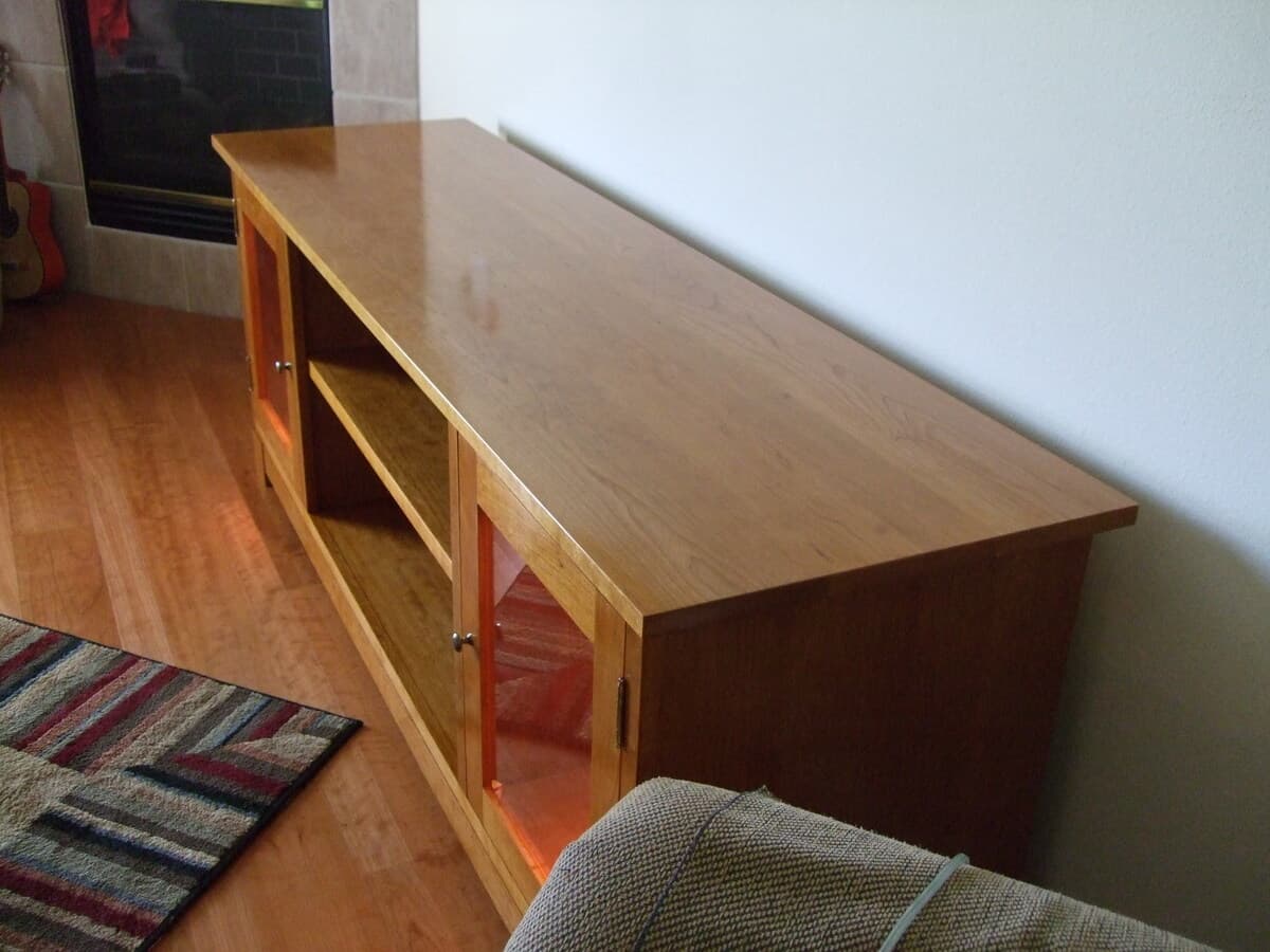 Cherry TV stand profile view highlighting the top surface and door panel proportions with visible wood grain detail