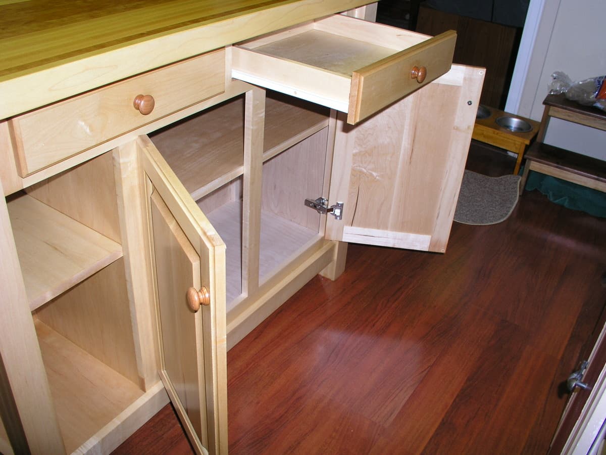 Full kitchen island with cherry work surface and hard maple frame, featuring cabinet storage, two drawers with copper hardware, and Waterlox finish