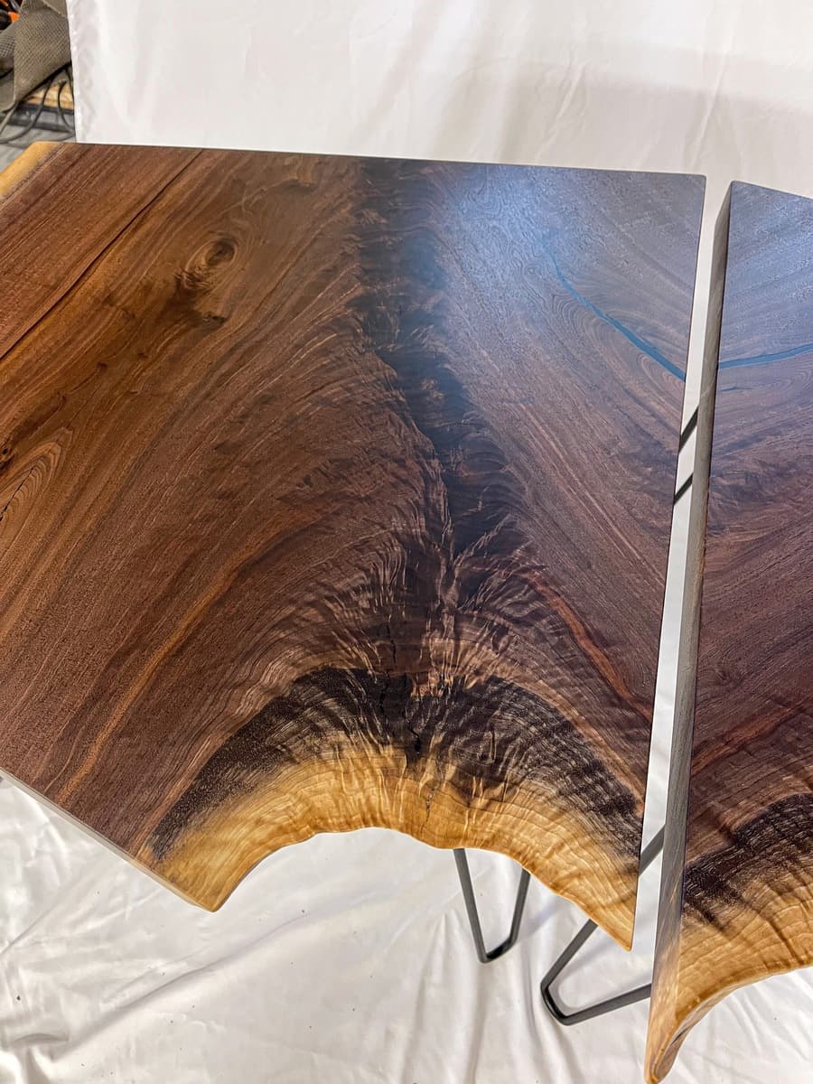 Live edge walnut end table in home setting positioned next to cream-colored upholstered chair with natural window lighting