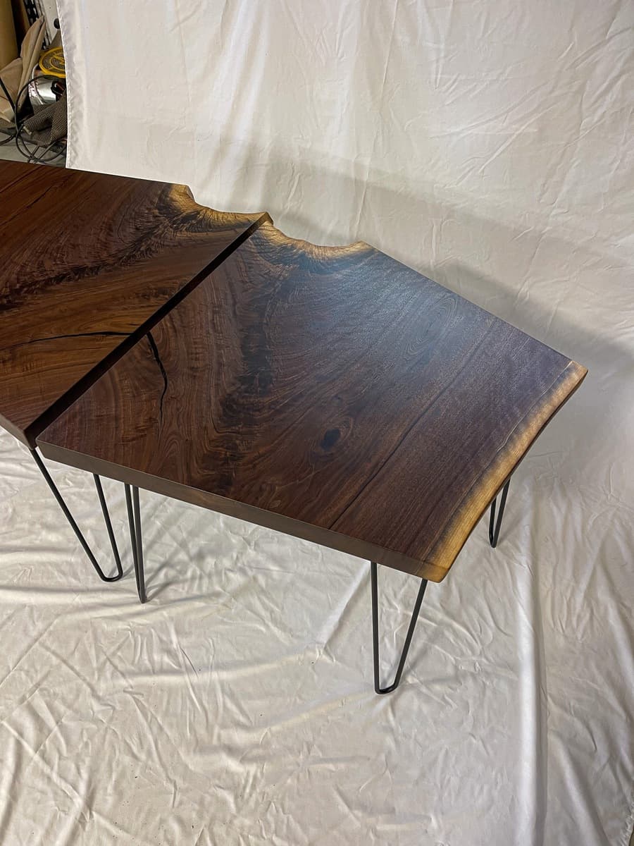 Close-up detail of live edge walnut end table showing dramatic bookmatched crotch grain with deep burgundy and blue-black figuring