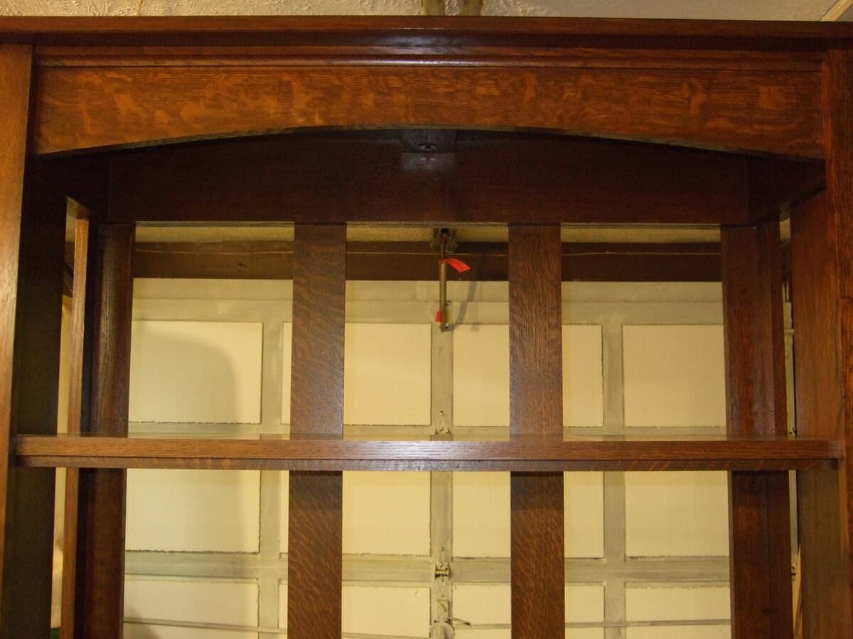 Mission bookcase detail showing finished mortise and tenon joint work on the bookcase frame, displaying the precise joinery and warm wood finish characteristic of Mission furniture design