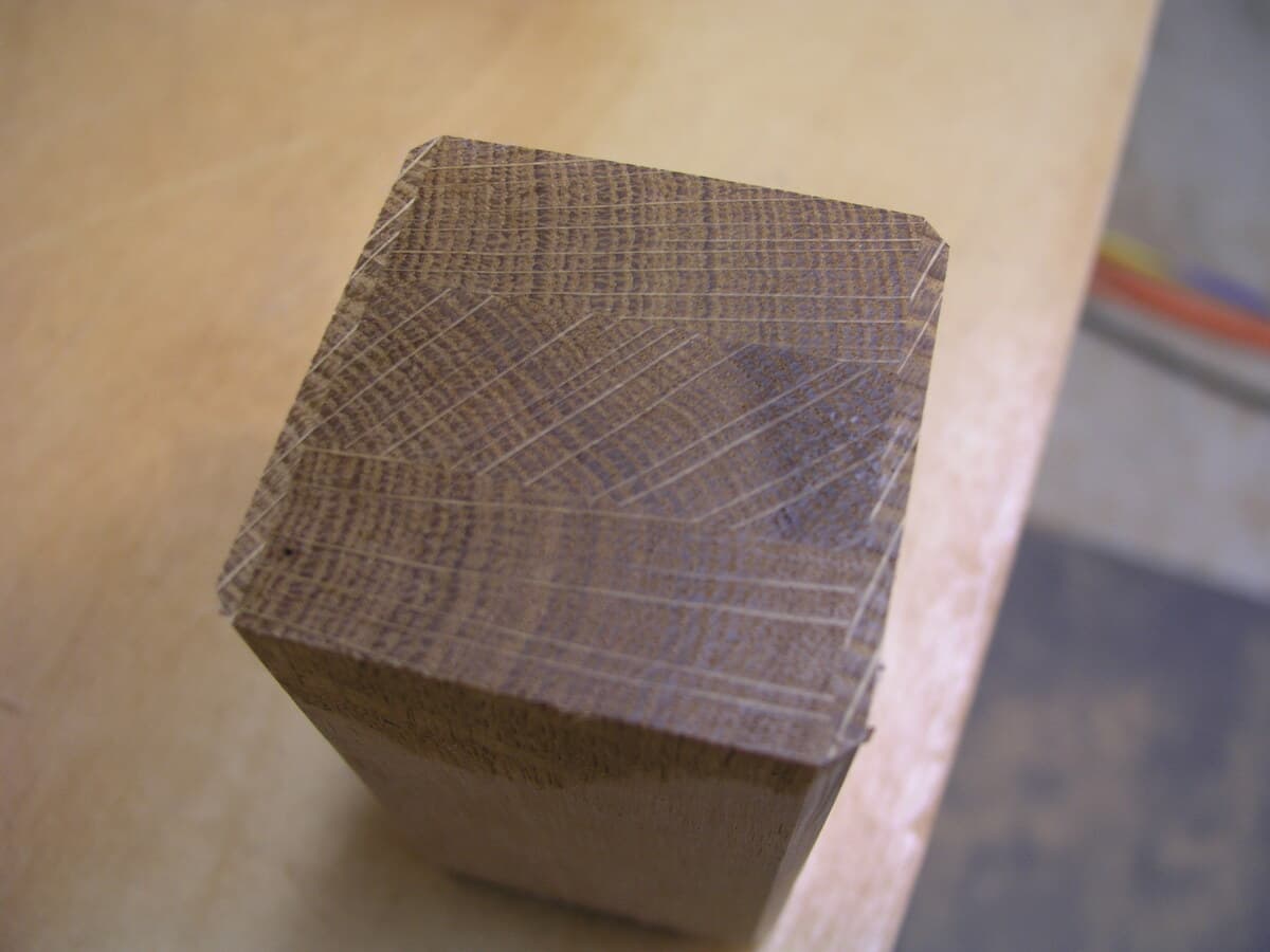 Close-up of a finished quarter-sawn white oak arm post showing the distinctive ray fleck figure pattern. The end grain reveals the cathedral-like grain pattern characteristic of quarter-sawn lumber. The piece demonstrates excellent grain selection and clean milling prior to assembly.