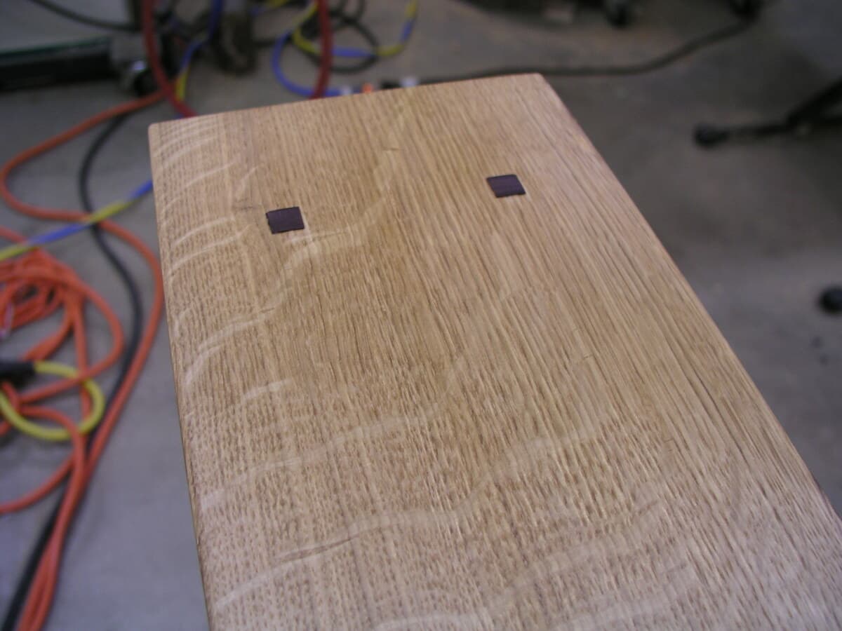 Interior view of the assembled sofa frame showing the support structure for cushions. The raw white oak frame reveals the seat rail system with multiple cross-supports, demonstrating the robust construction beneath the upholstery. Vertical slat back panels are visible on both ends with finish materials visible in the background workshop.