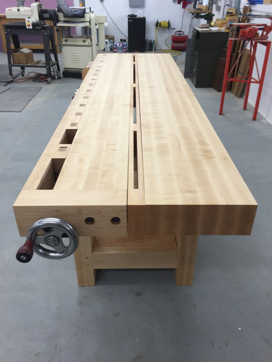 End view of Roubo workbench showing massive maple leg with circular cutout for leg vise hardware and bench dog holes along front edge