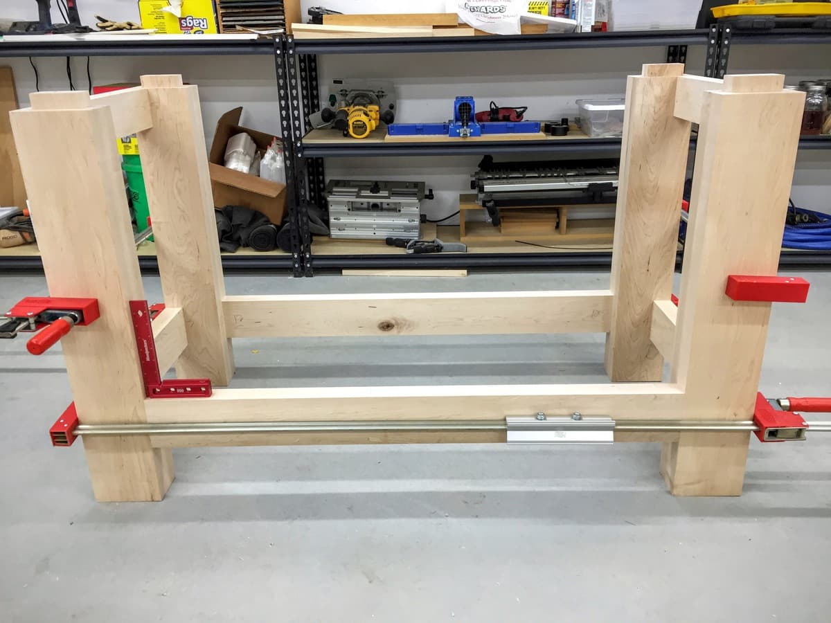 Maple legs with carved mortises displayed on sawhorses, showing layout marks and hardware cutouts