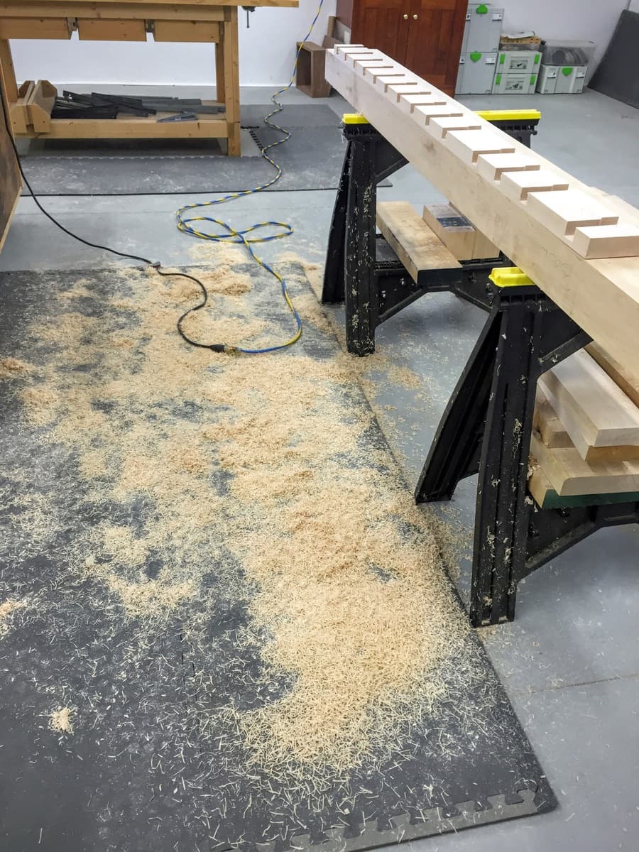 Workshop view showing array of red Bessey parallel clamps gluing up workbench top, with component parts on sawhorses